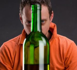Alkoholik patrzący na butelkę z winem.